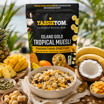 TassieTom Island Gold Tropical Muesli packaging with a bowl of muesli and tropical fruits on a wooden table.