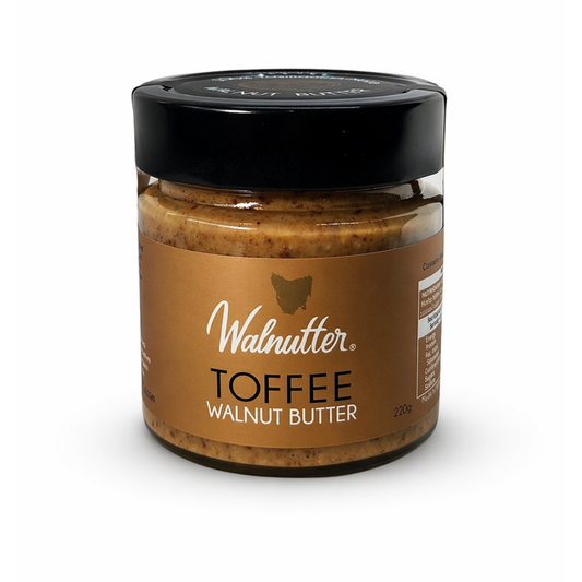 Jar of toffee walnut butter with a black lid on a white background